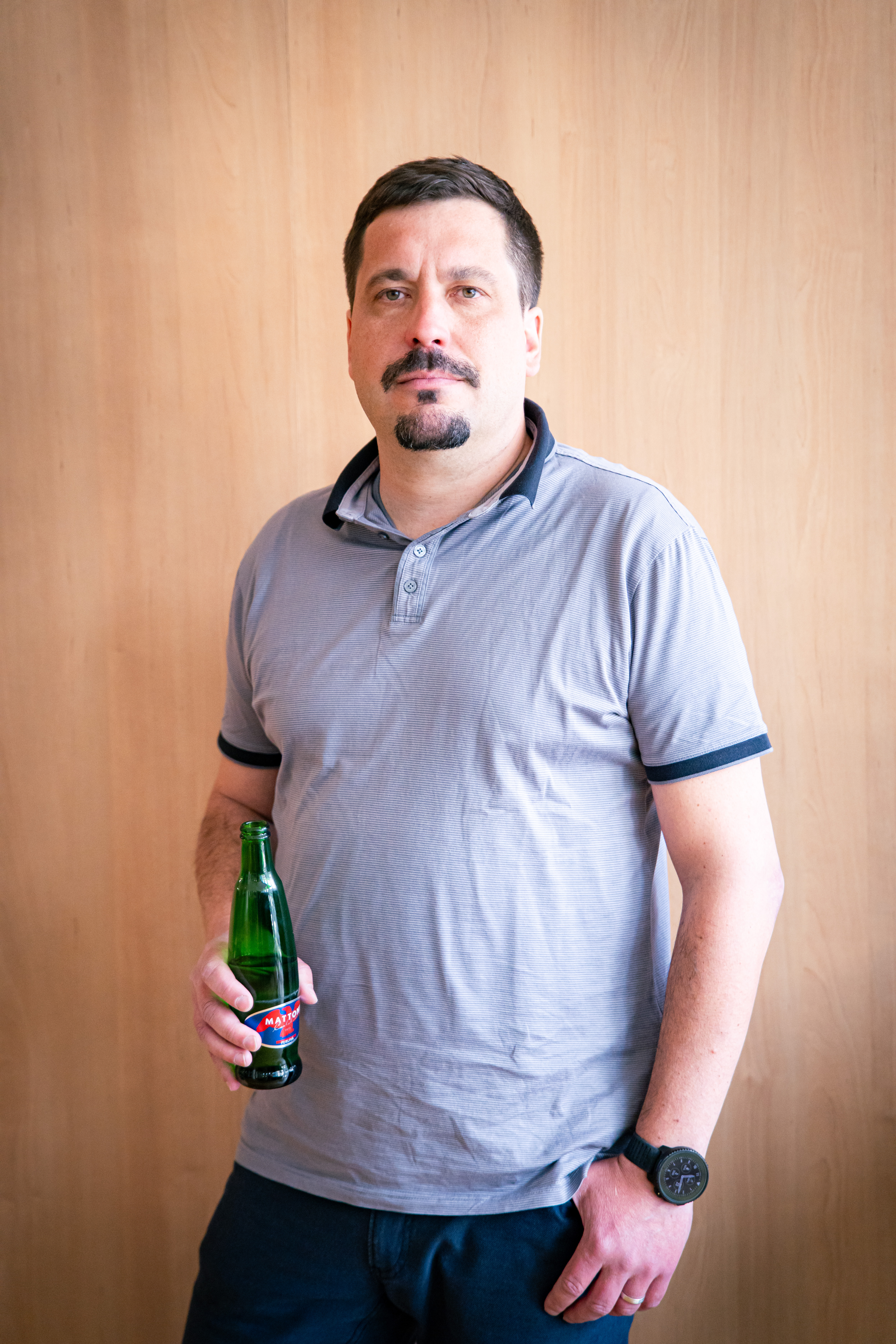 Jan Medek, Group HR Director ve společnosti Mattoni 1873, v pražských kancelářích na Palmovce — modré tričko s límečkem, lahev Mattoni v ruce. Z natáčení 16. dílu HR Vibecheck od VERYGUD.